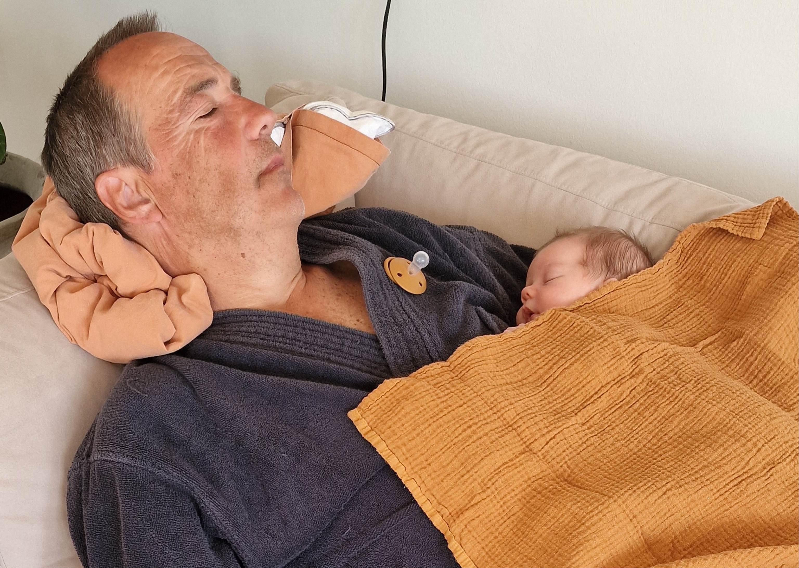 A person lying in bed with a baby

Description automatically generated